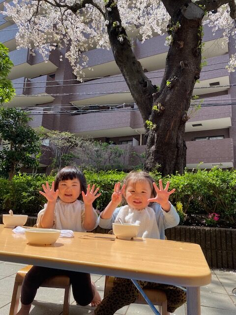 エントランスの桜の木の下でみんなで食べるお昼給食